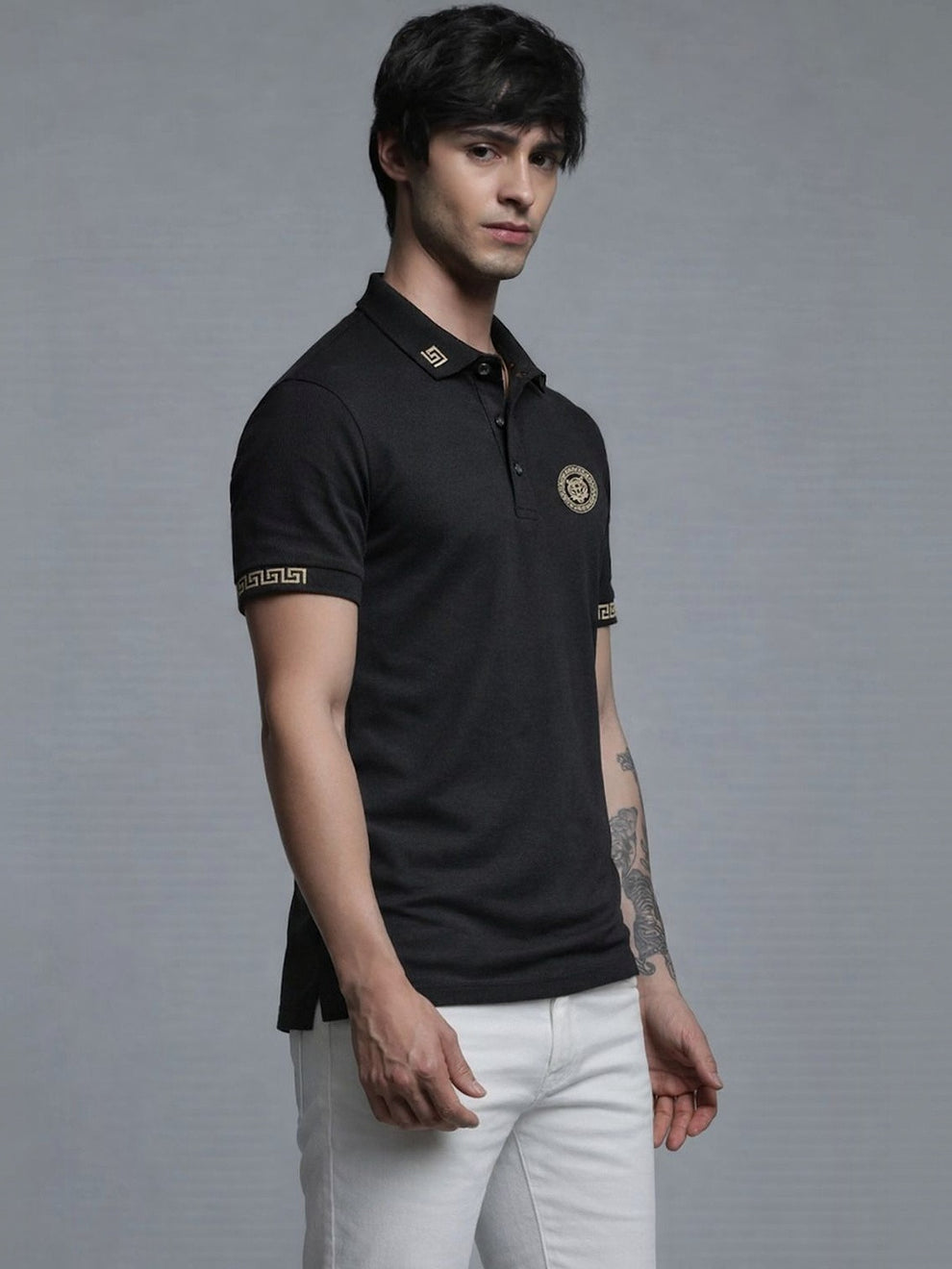 Man wearing a black polo shirt with gold accents on a gray background