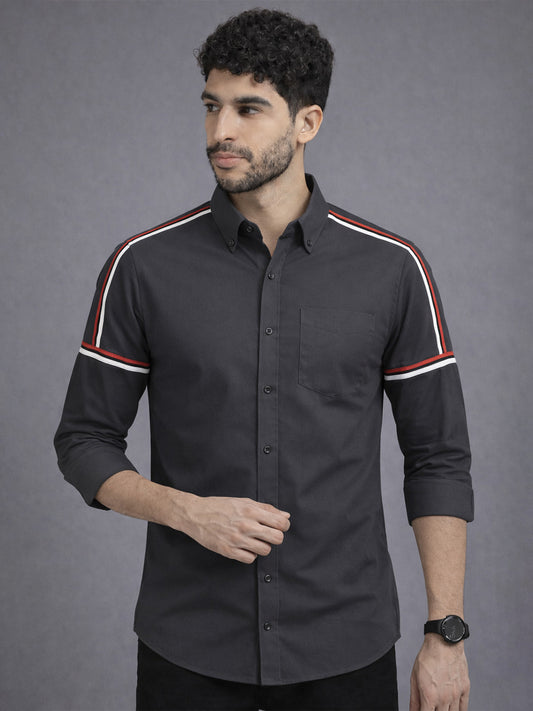 Man wearing a black shirt with white and red stripes on a gray background