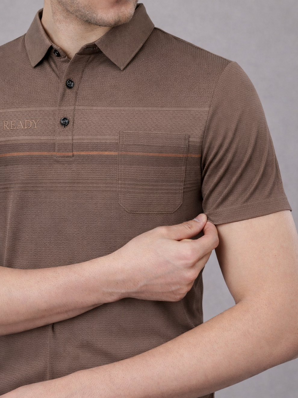 Brown polo shirt worn by a person on a gray background