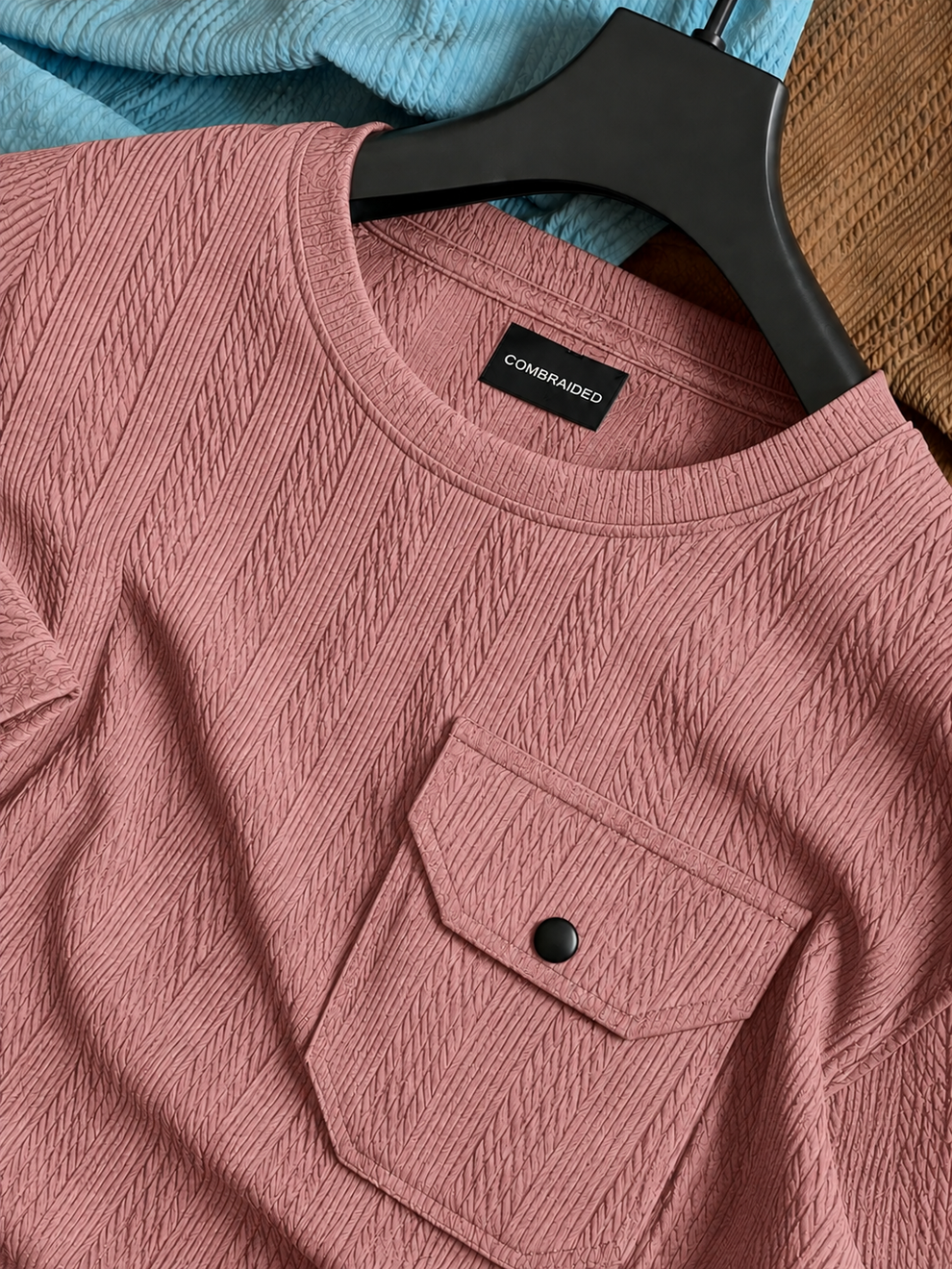 Pink textured shirt with a brand label on a hanger against a blurred background