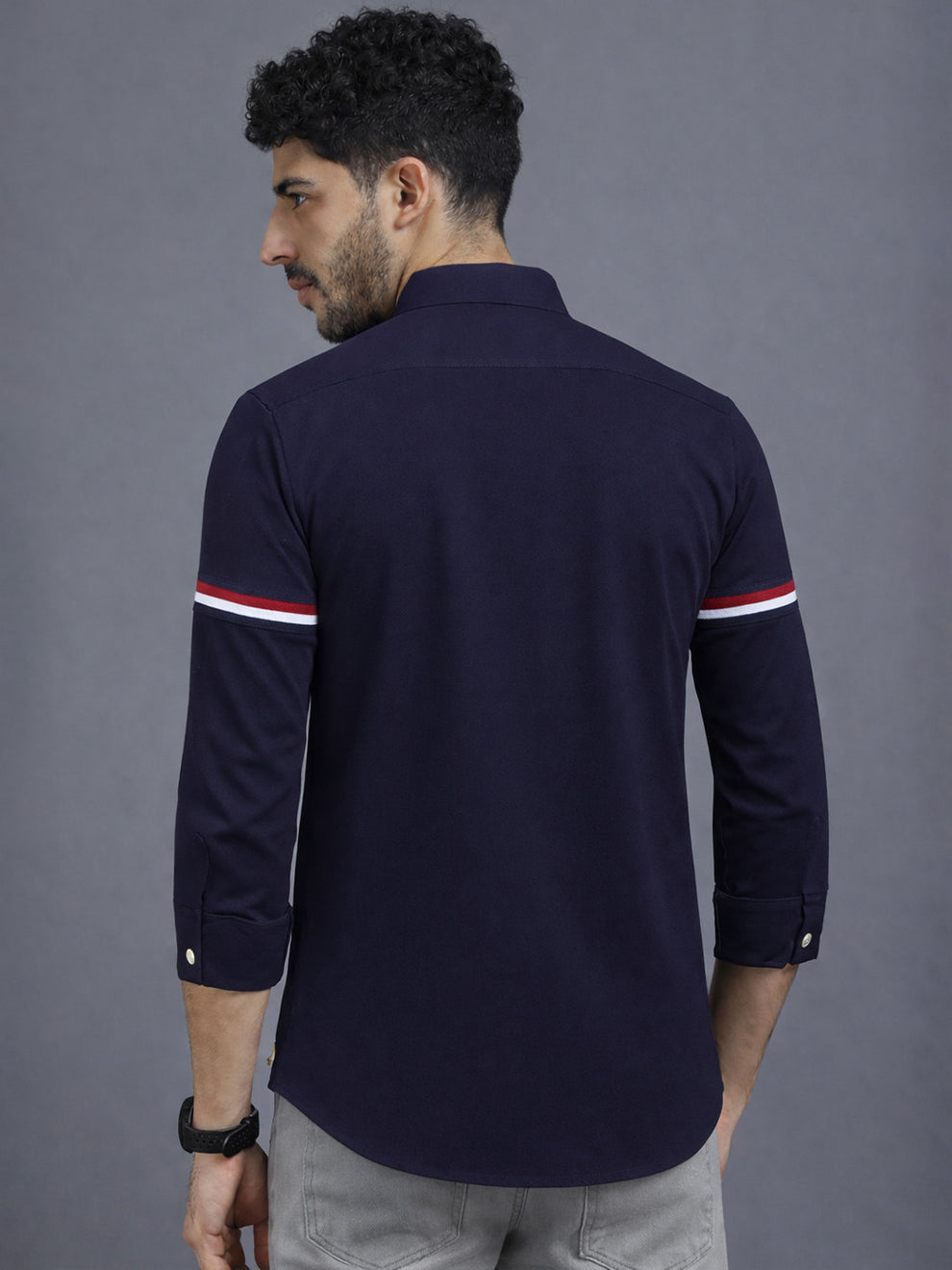 Man wearing a navy blue long-sleeve shirt with white stripes on gray background