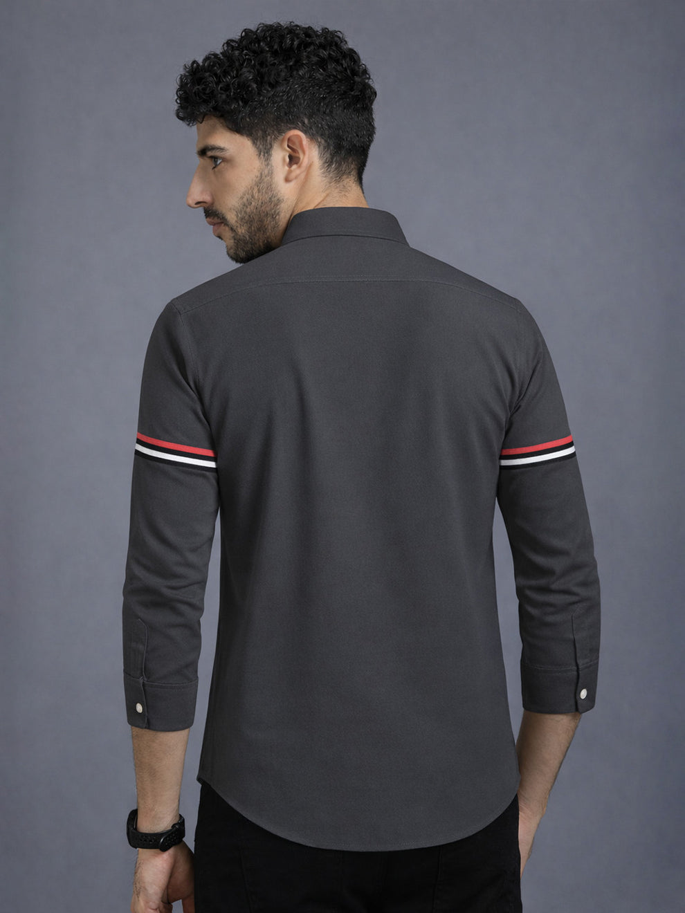 Man wearing a dark gray shirt with striped sleeves against a gray background