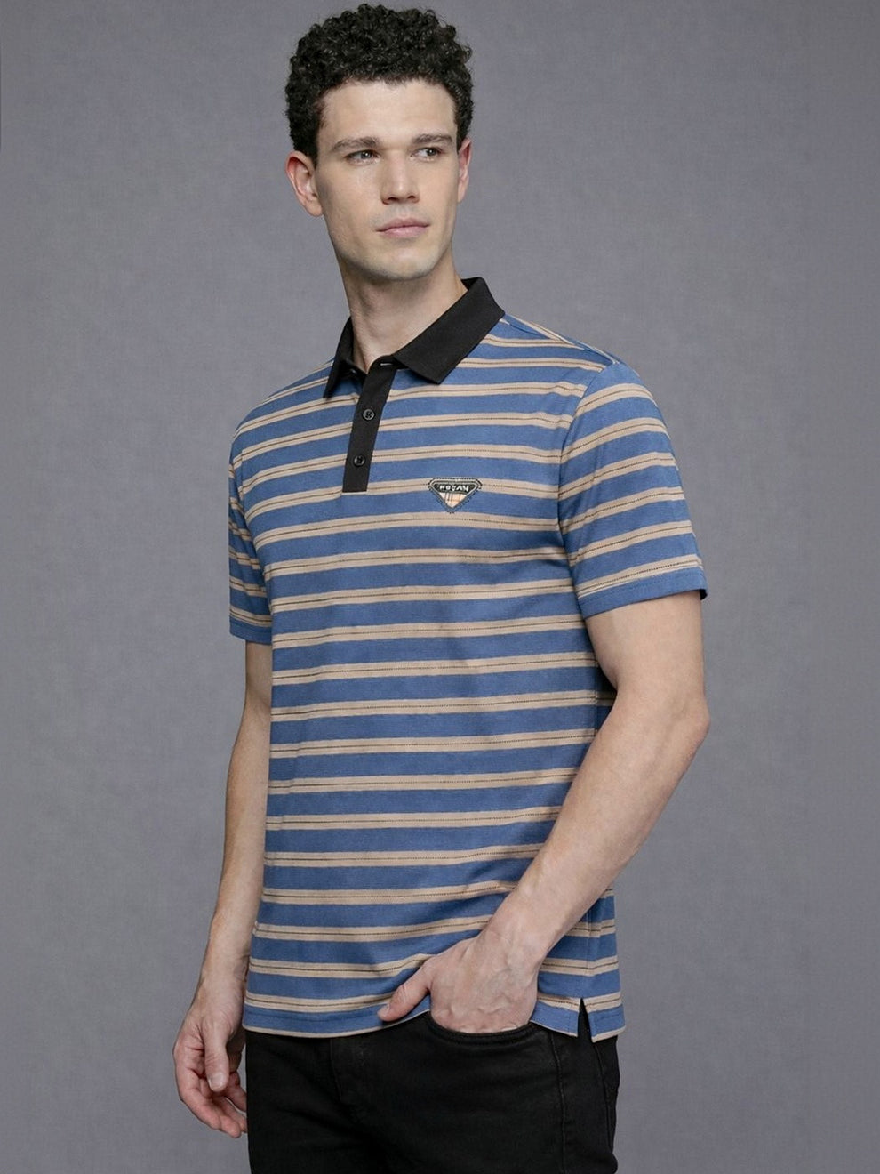 Man wearing a blue and beige striped polo shirt with a brand logo on a gray background