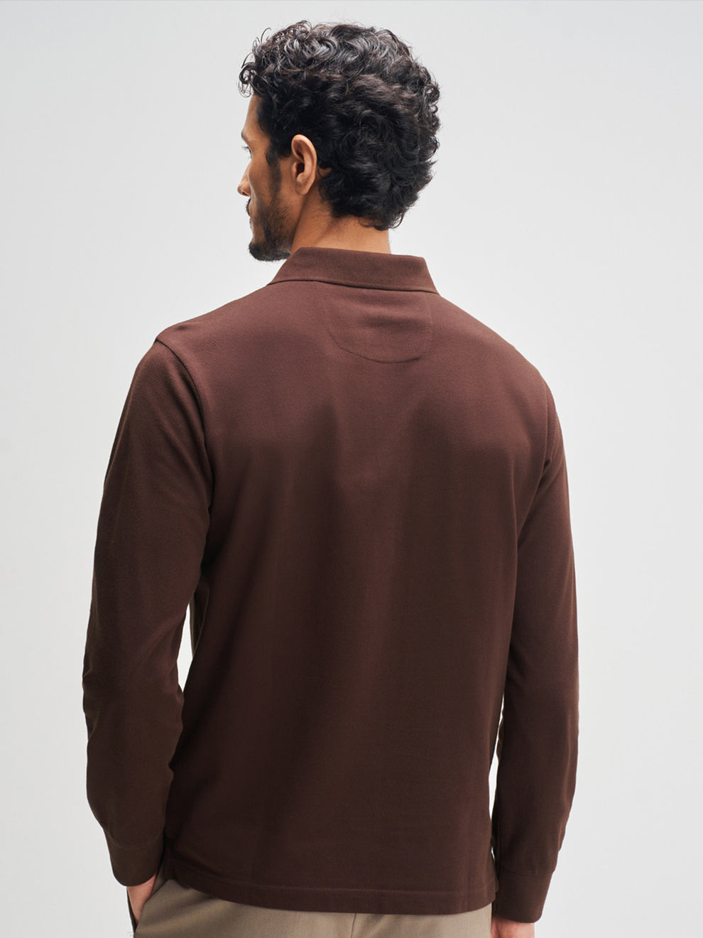 Man wearing a brown long-sleeve shirt against a light gray background