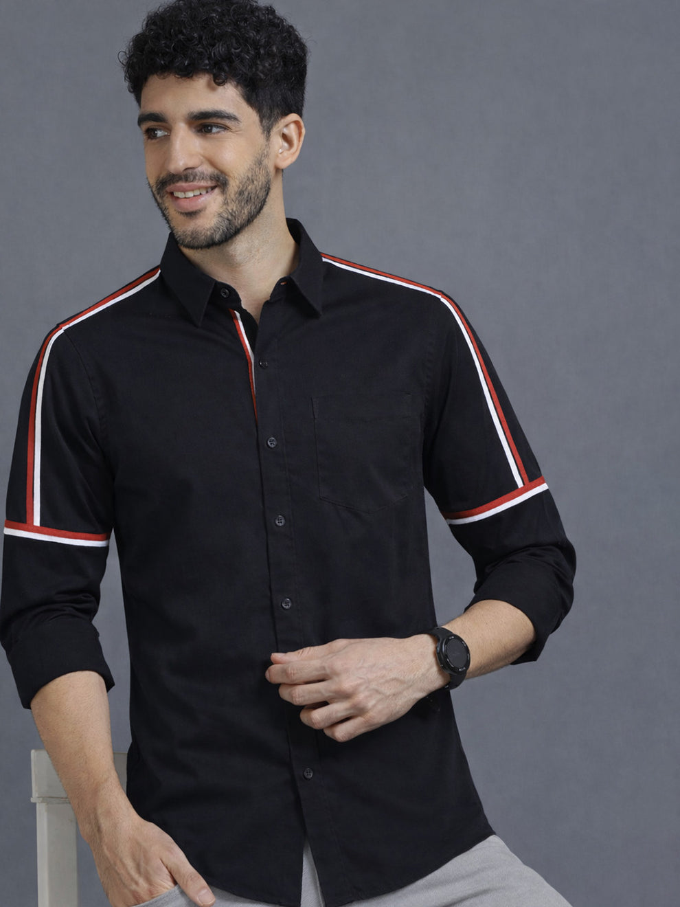 Man wearing a black shirt with red and white stripes on a gray background