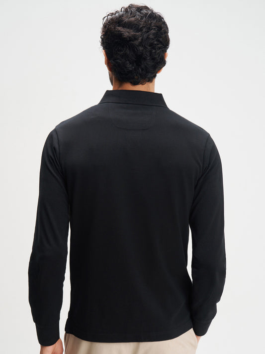 Person wearing a black long-sleeve shirt against a white background