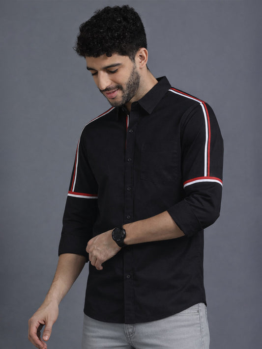 Man wearing a black shirt with white and red stripes on a gray background