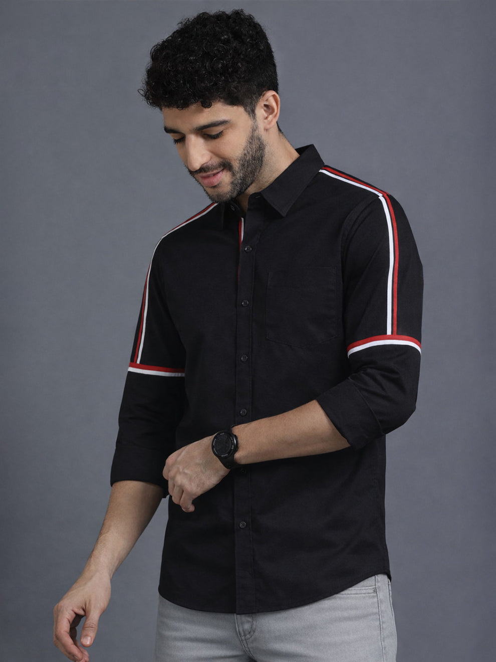 Man wearing a black shirt with white and red stripes on a gray background