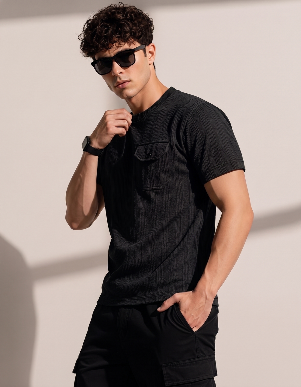 Man wearing a black t-shirt and sunglasses against a plain background