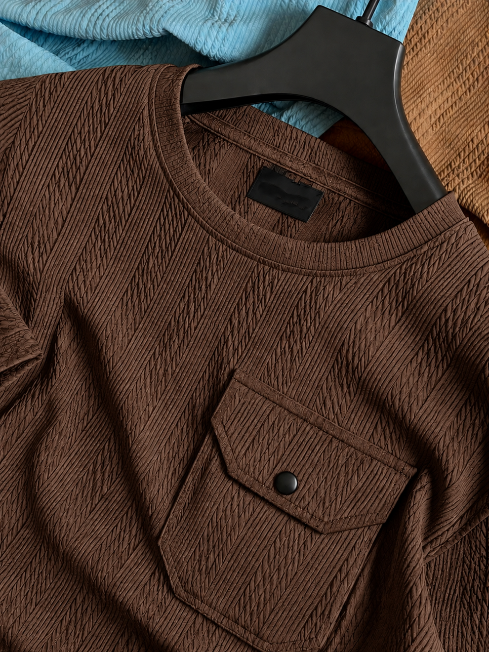 Brown textured shirt on a hanger with a blurred blue fabric background