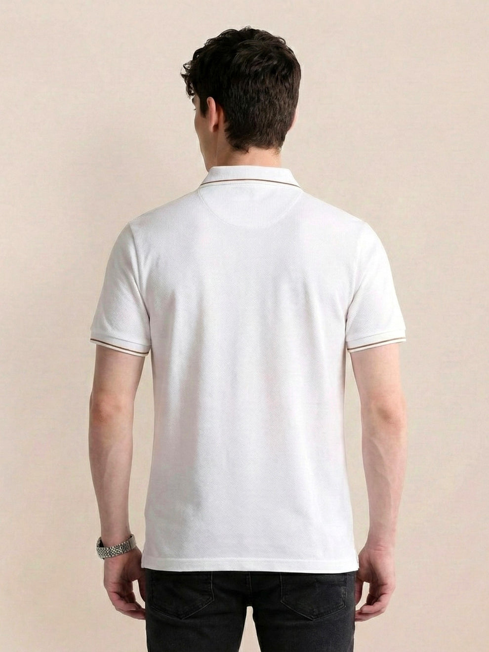 Man wearing a white polo shirt against a beige background