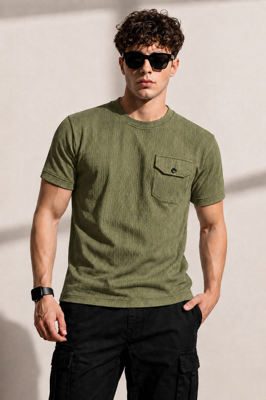 Man wearing an olive green t-shirt with a pocket and sunglasses against a plain background