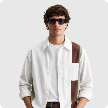 Man wearing a white unbuttoned shirt over a white t-shirt and sunglasses.