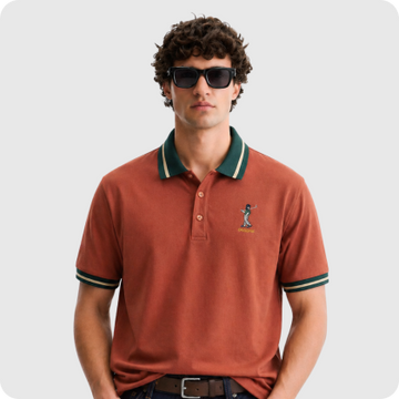 Man wearing a rust-colored polo shirt with green collar detail and sunglasses.