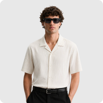 Man wearing a white textured polo shirt and sunglasses.