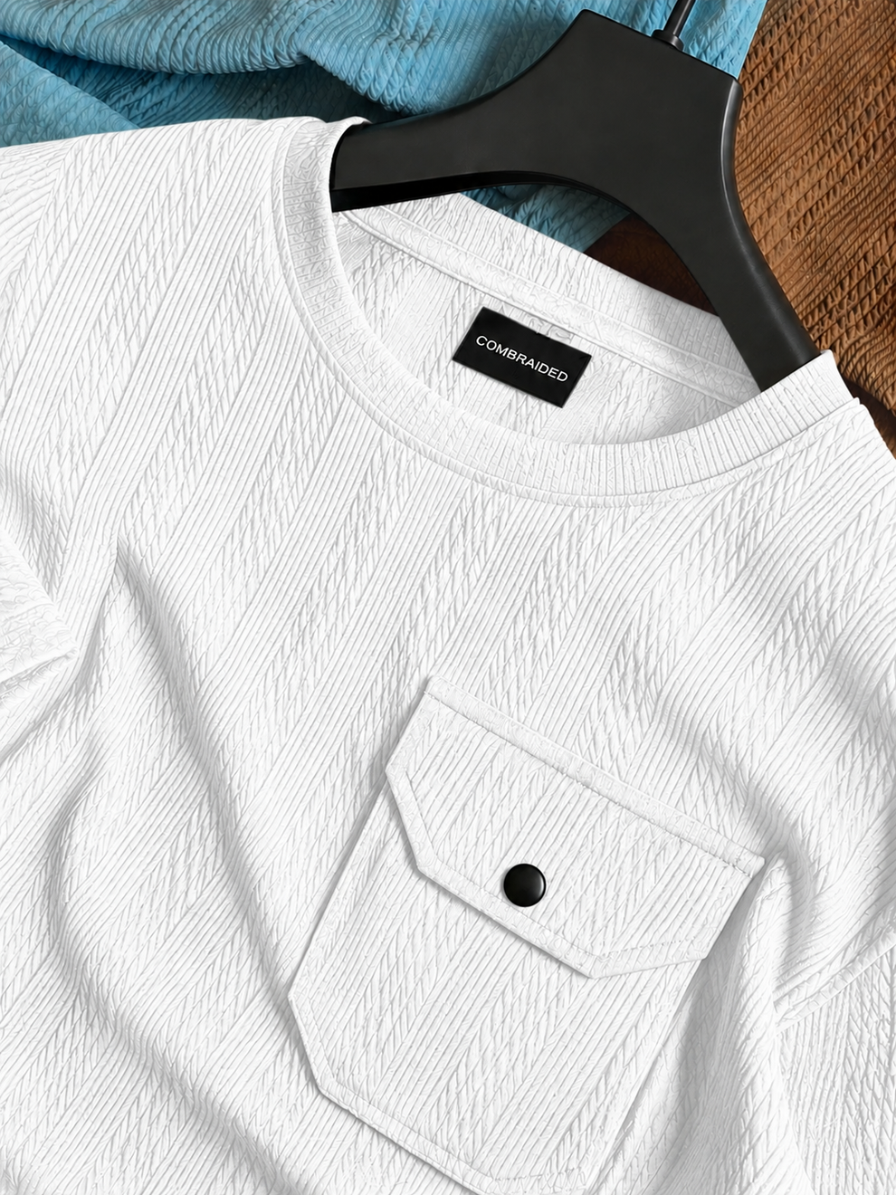 White textured shirt with a black button on a hanger against a blurred background