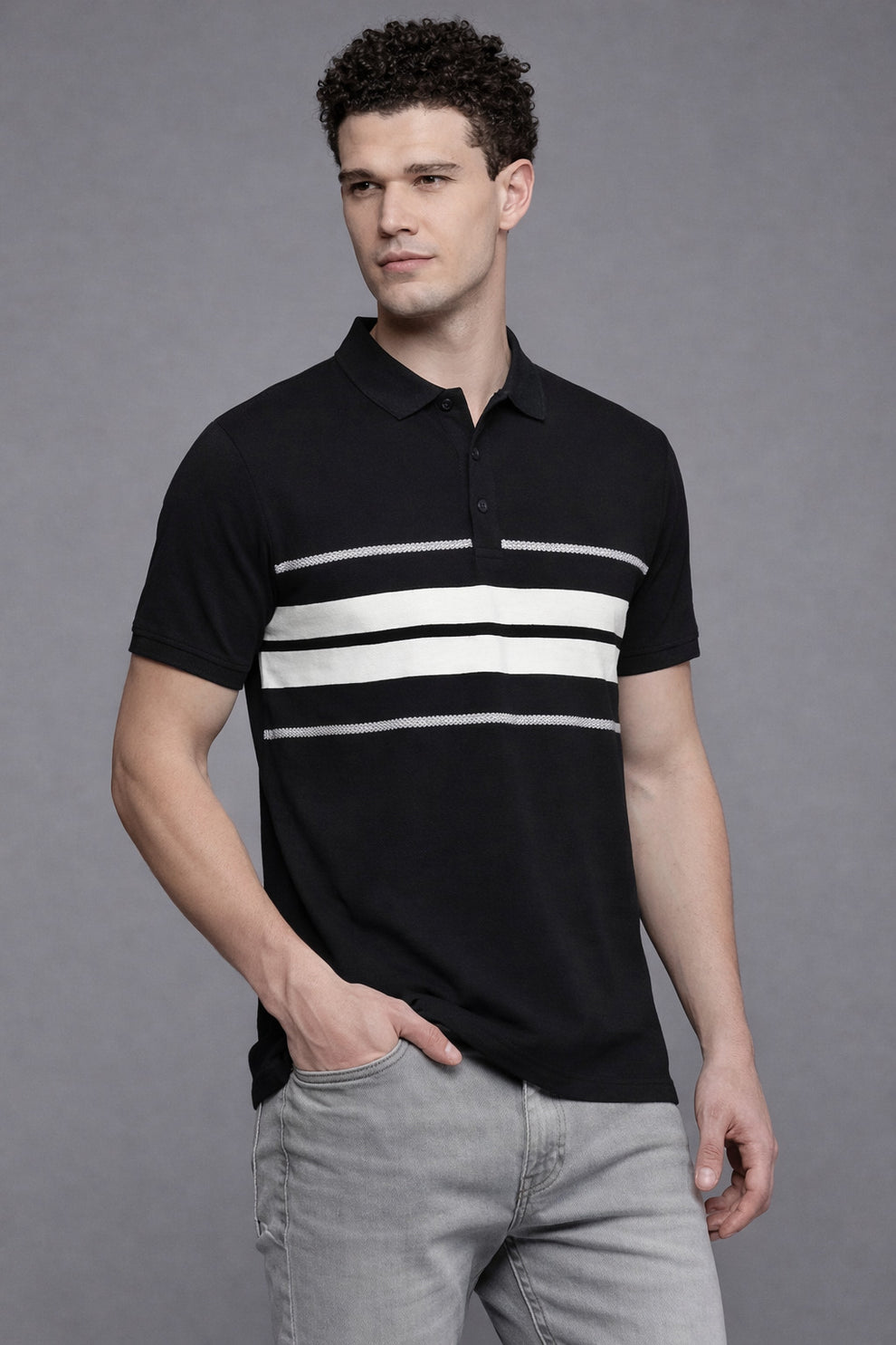 Man wearing a black polo shirt with white stripes and gray pants against a gray background