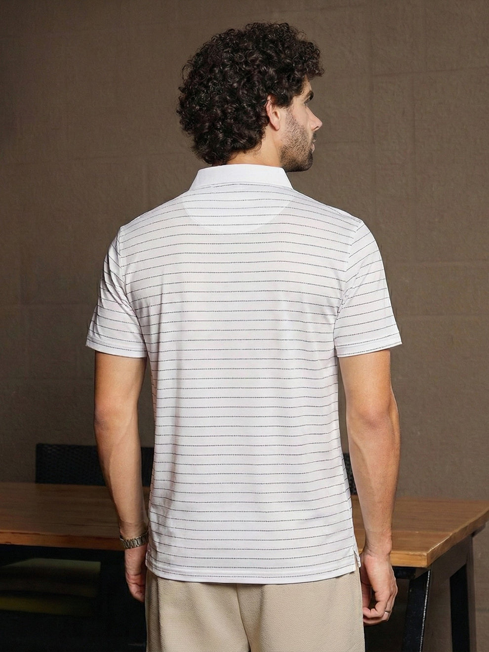 Man wearing a striped polo shirt in an indoor setting