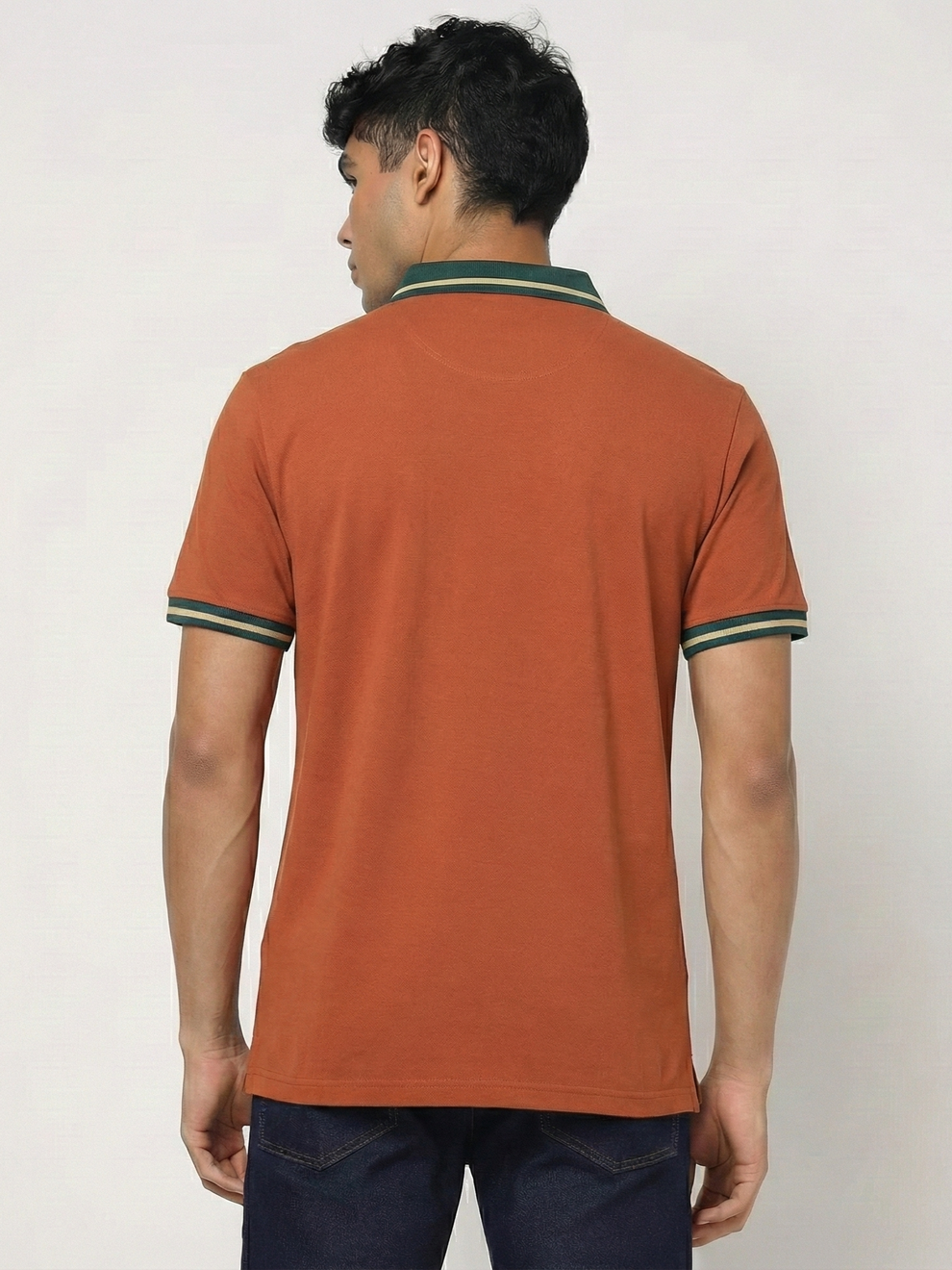 Man wearing a Orange polo shirt with green trim on a plain background