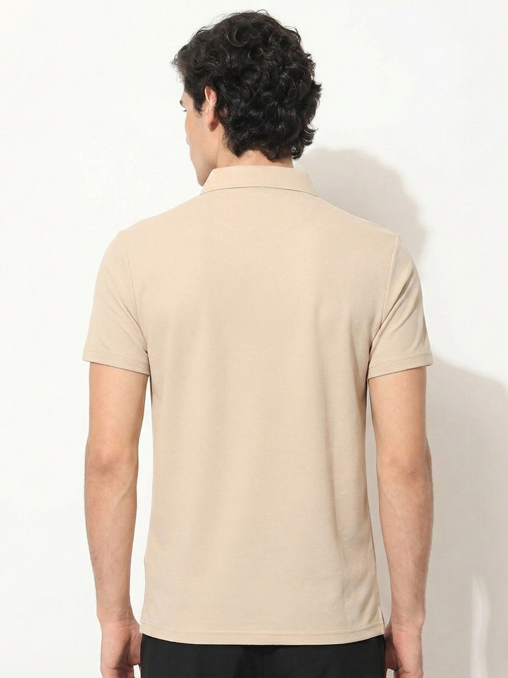 Man wearing a beige polo shirt against a white background