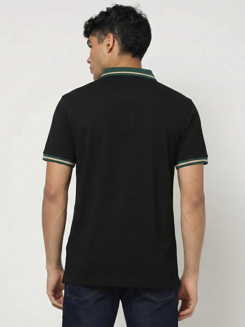Man wearing a black polo shirt with green trim on a plain background