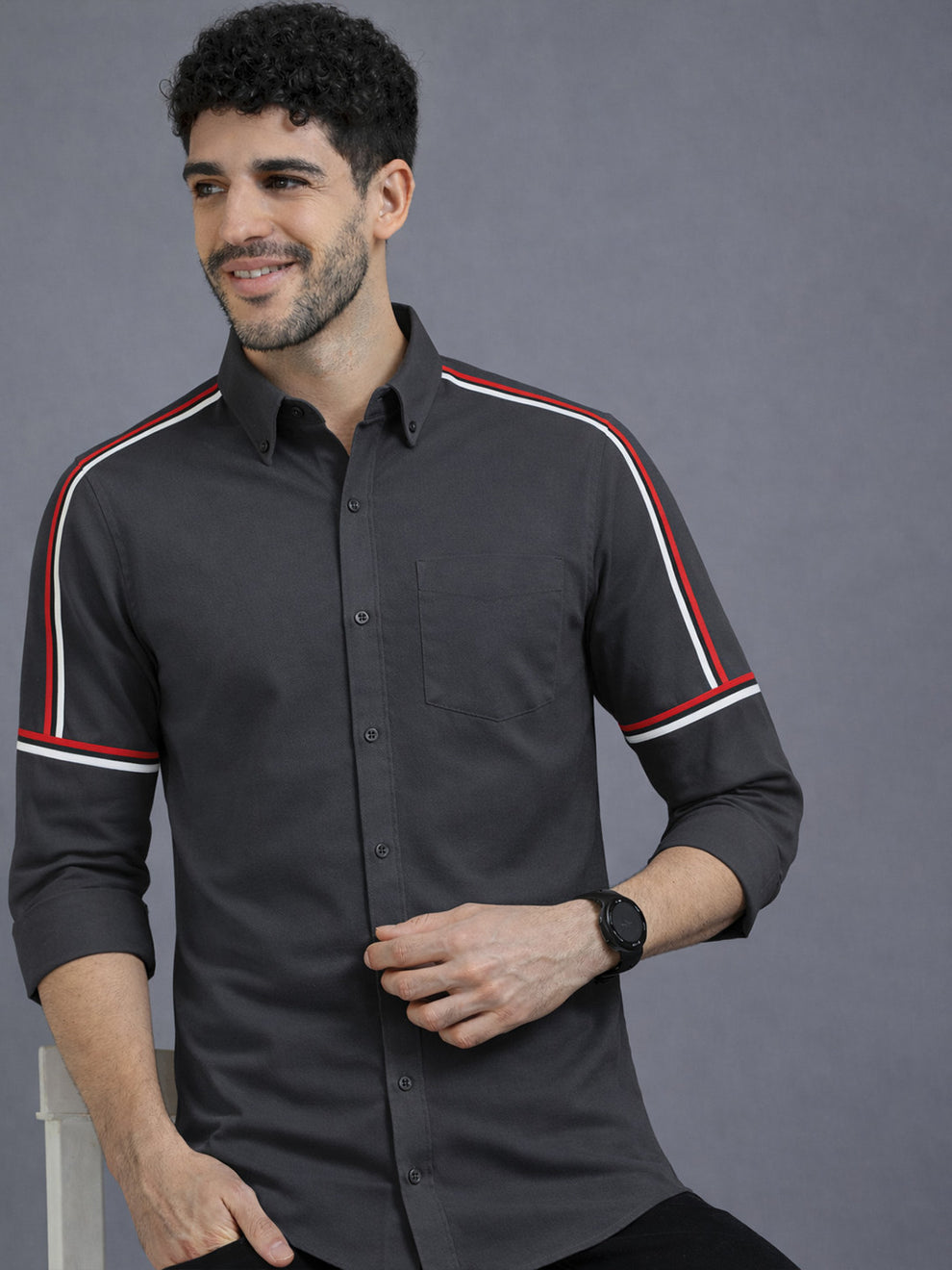 Man wearing a black shirt with red and white stripes on a gray background