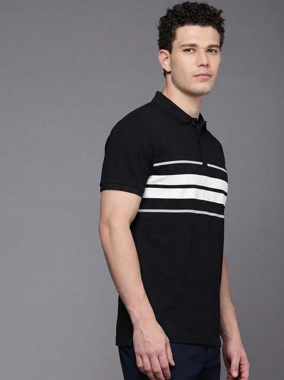 Man wearing a black polo shirt with white stripes on a gray background