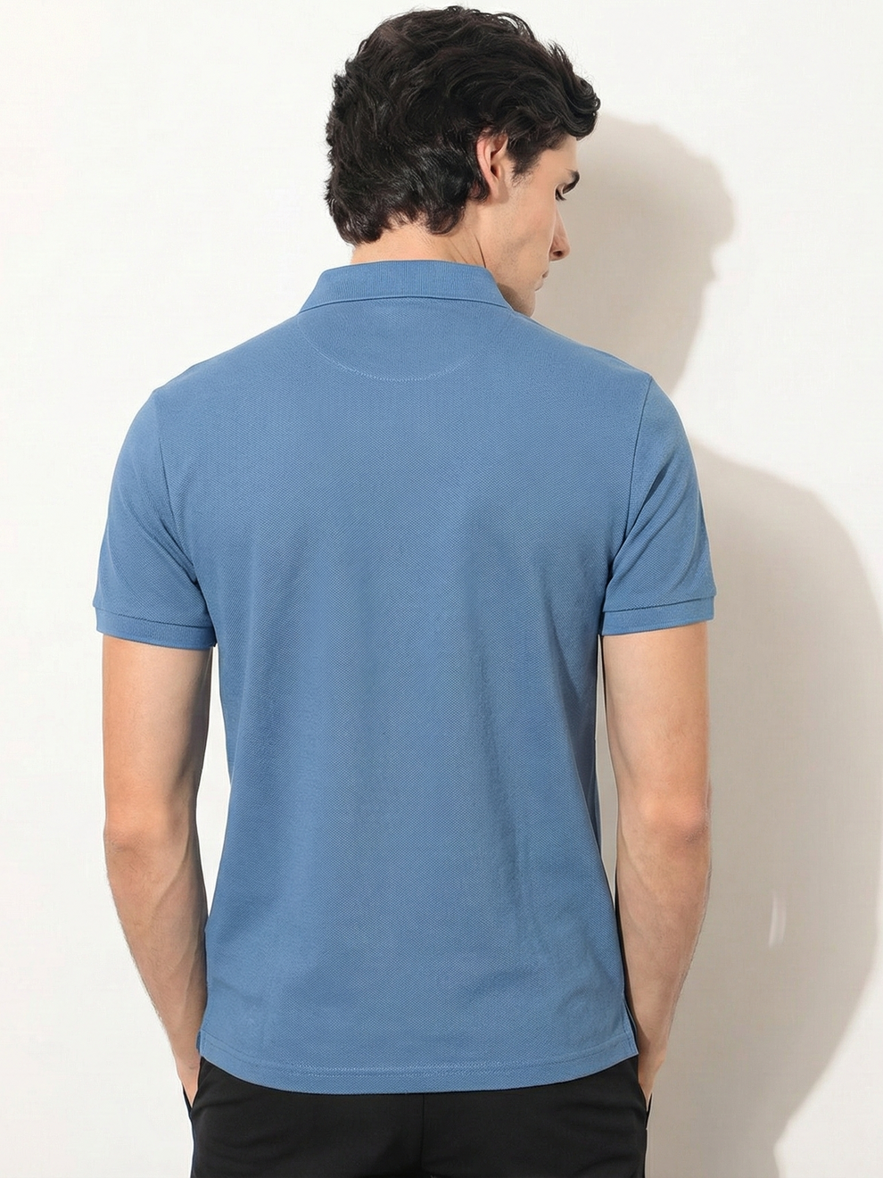 Man wearing a blue polo shirt against a white background