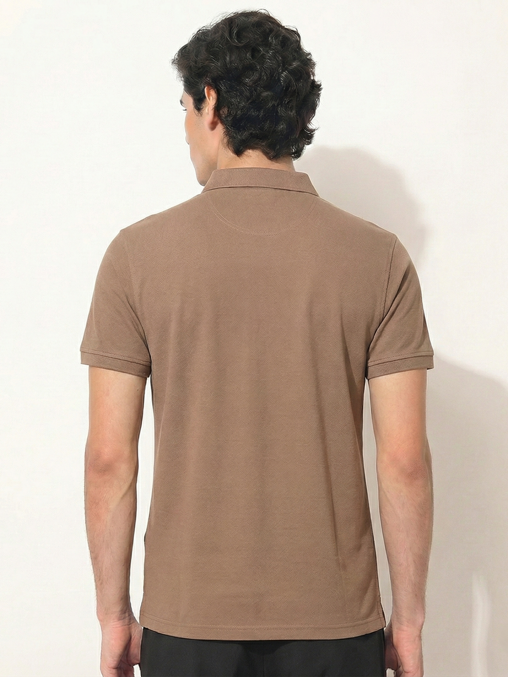 Man wearing a brown polo shirt against a white background