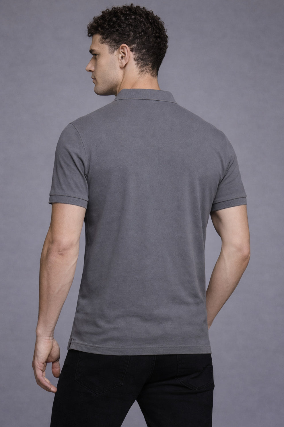 Man wearing a gray polo shirt against a gray background