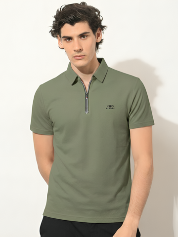 Man wearing a green polo shirt with a small logo on a white background