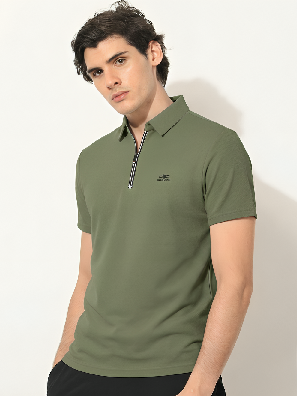 Man wearing a green polo shirt with a small logo on a white background