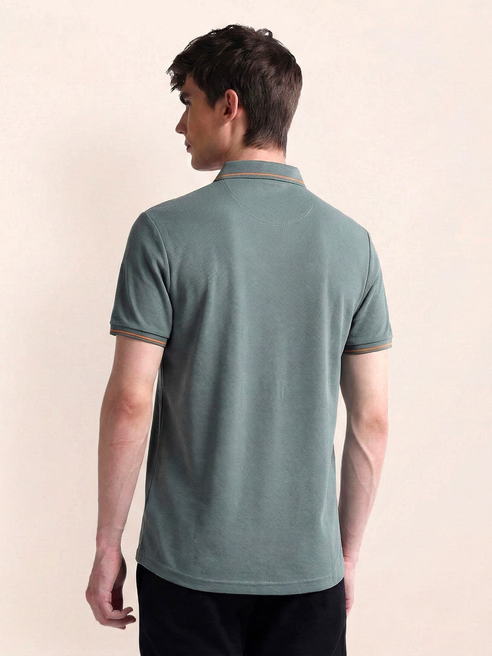 Man wearing a green polo shirt on a beige background