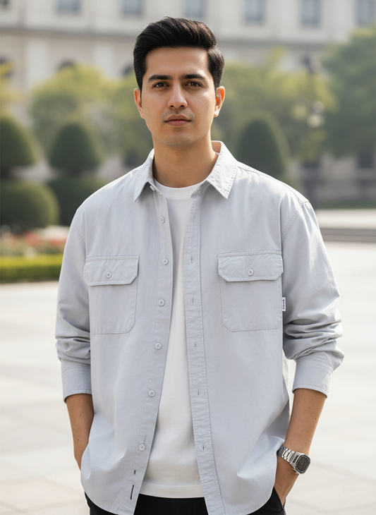 Man wearing a light gray shirt with a blurred background