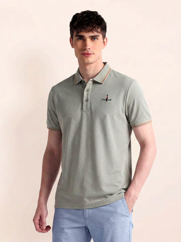 Man wearing a light green polo shirt with a small logo on a beige background
