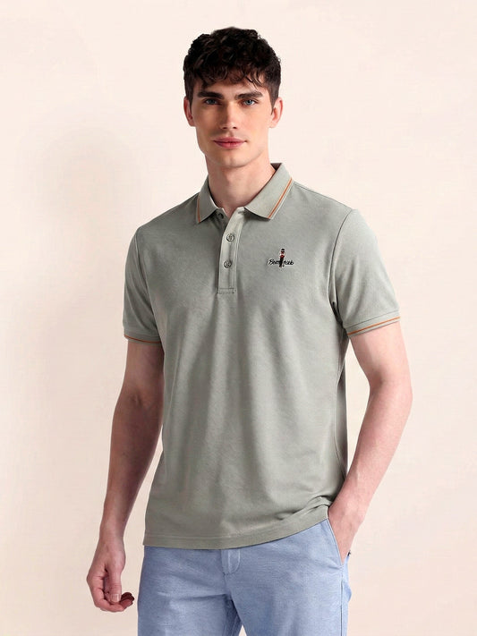 Man wearing a light green polo shirt with a small logo on a beige background