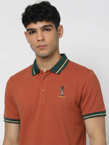 Man wearing a orange polo tshirt with green accents and a logo on a plain background
