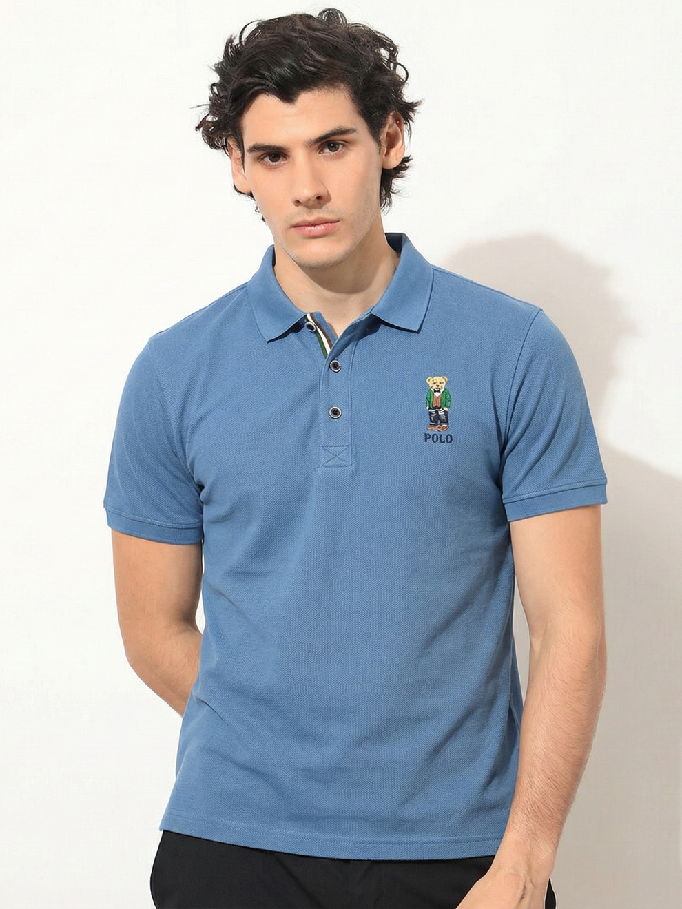 Man wearing a blue polo shirt with a logo on a white background
