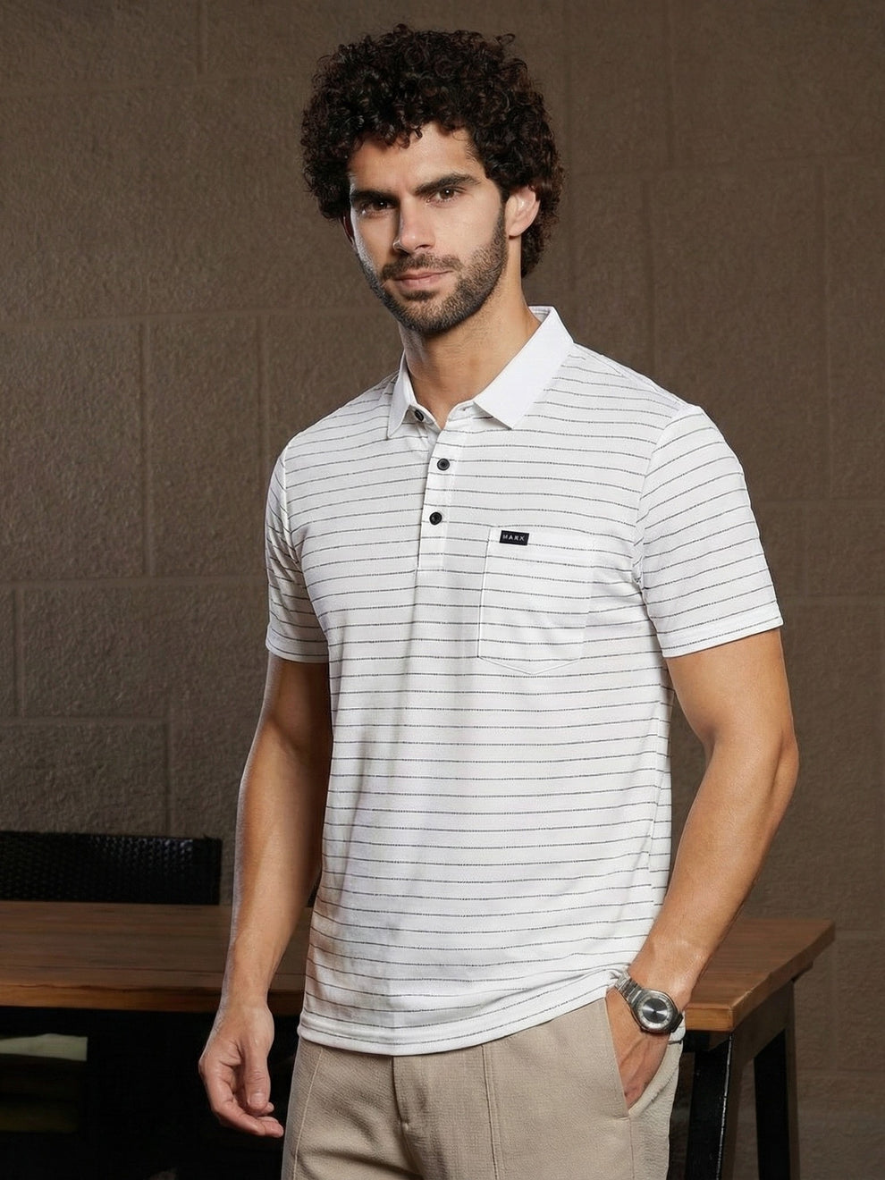 Man wearing a white striped polo shirt with a brand logo against a brown background