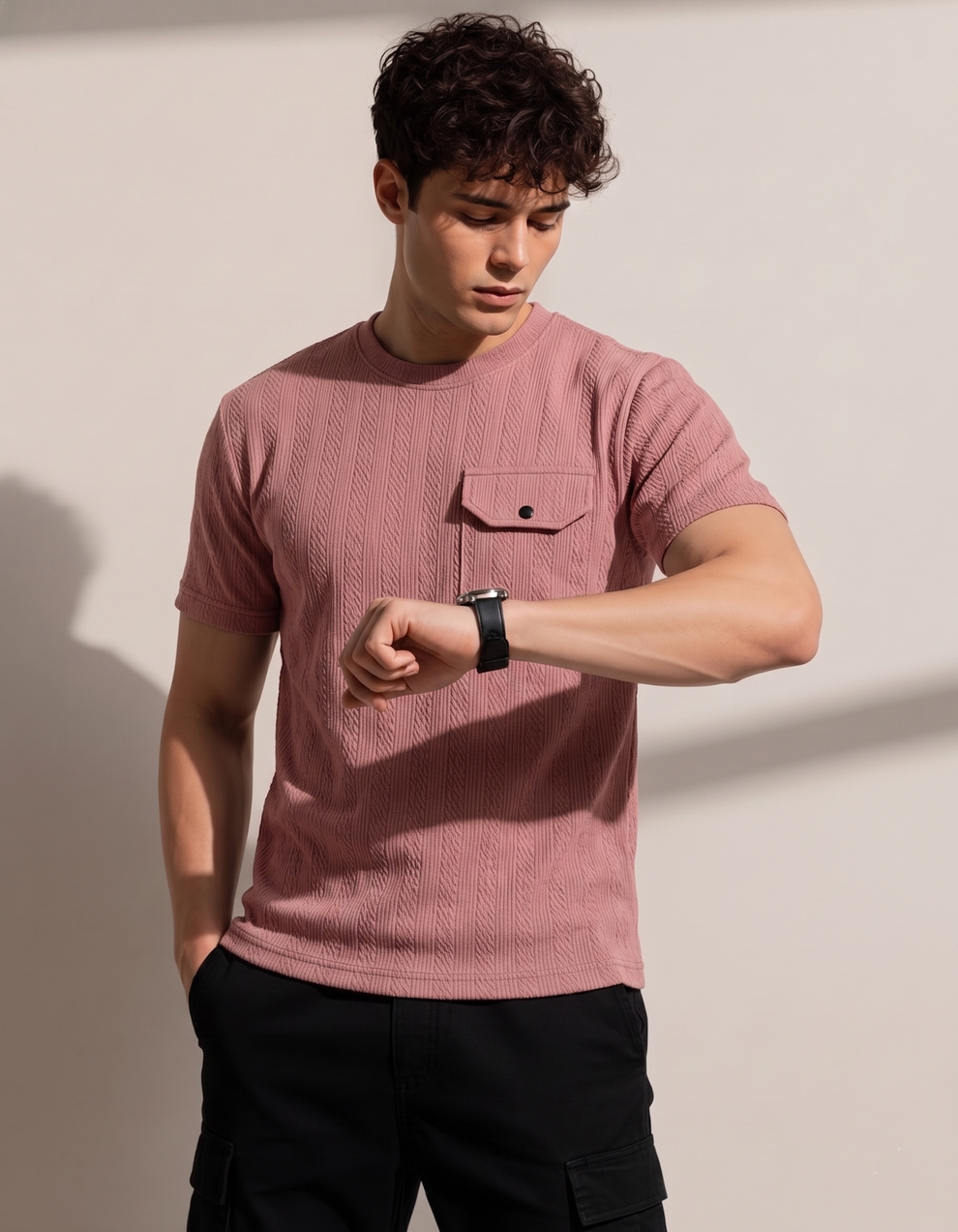 Man wearing a pink textured shirt and black pants against a plain background