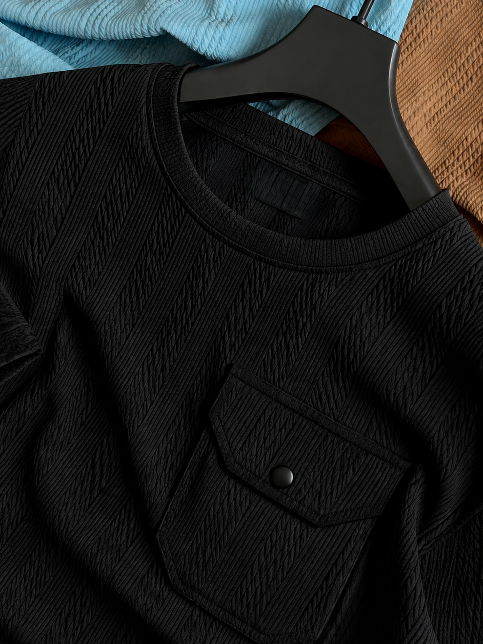Black shirt on a hanger with a textured surface in the background