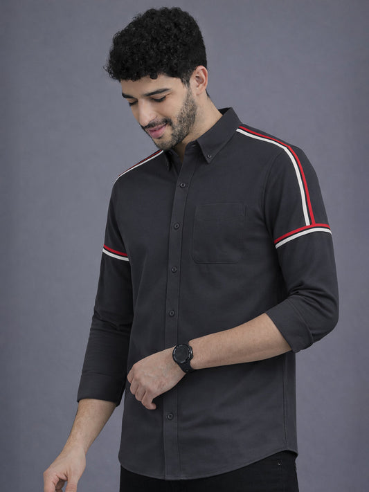 Man wearing a black shirt with red and white stripes on a gray background