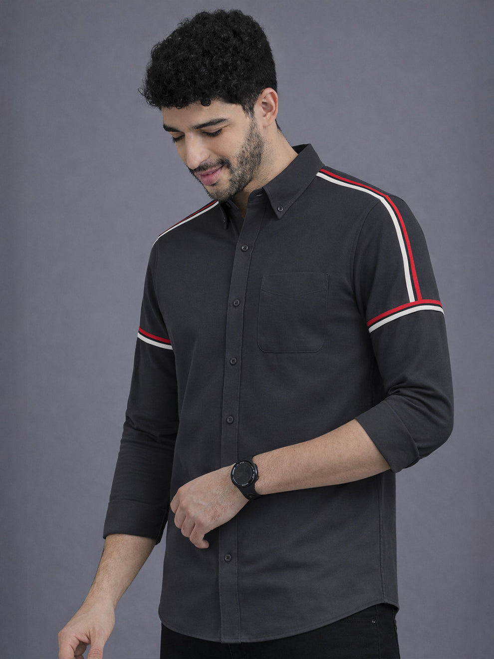 Man wearing a black shirt with red and white stripes on a gray background