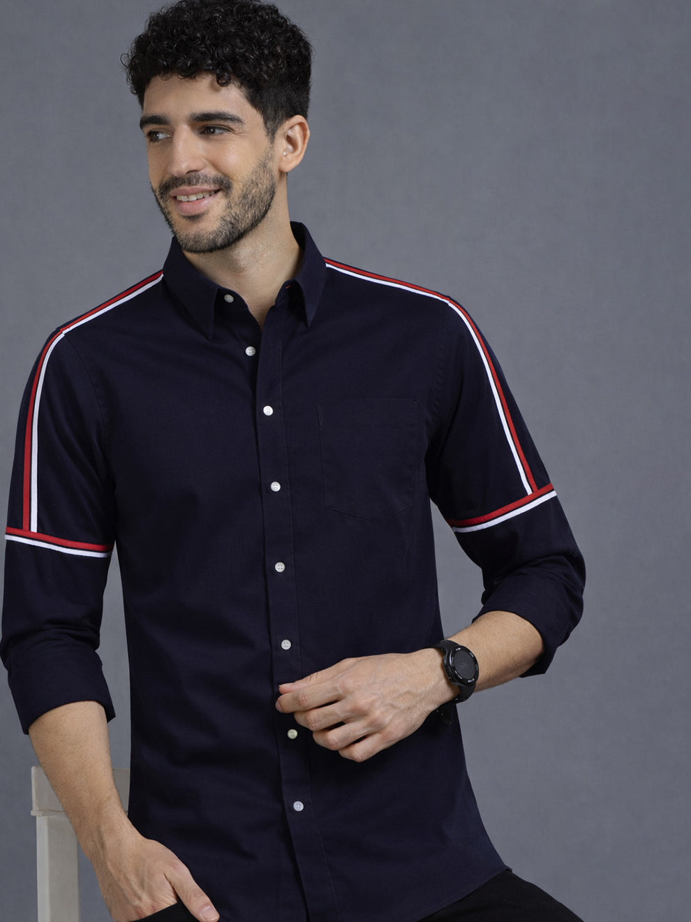 Man wearing a navy shirt with red and white stripes on a gray background