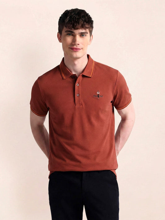 Man wearing a brown polo shirt with a small logo on a beige background