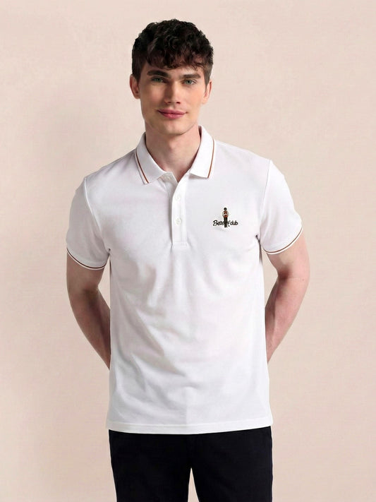 Man wearing a white polo shirt with a logo on a beige background