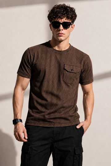 Man wearing a brown t-shirt and sunglasses against a plain background