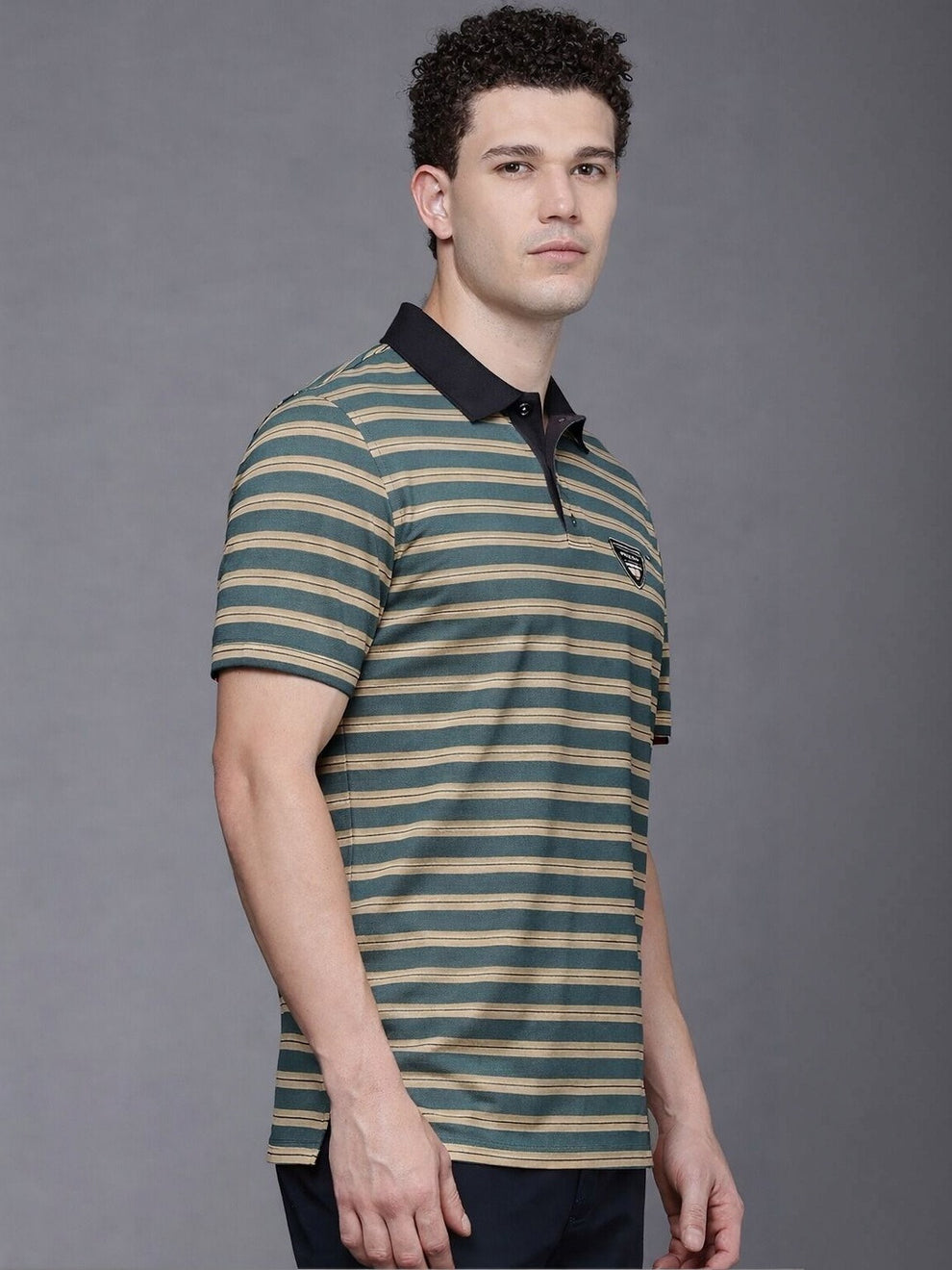 Man wearing a striped polo shirt against a gray background