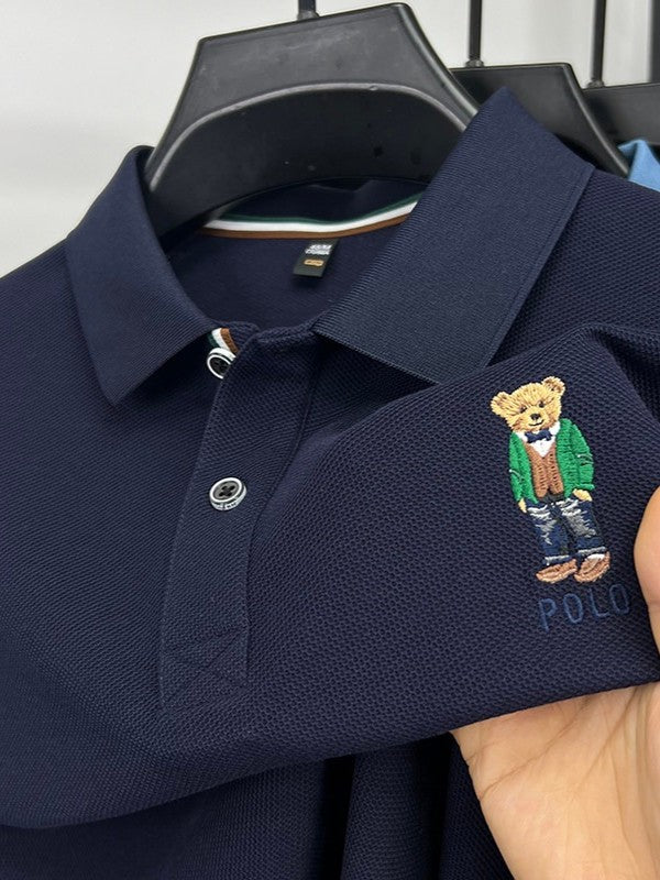 Navy blue Polo Ralph Lauren polo shirt with embroidered bear design on a hanger.