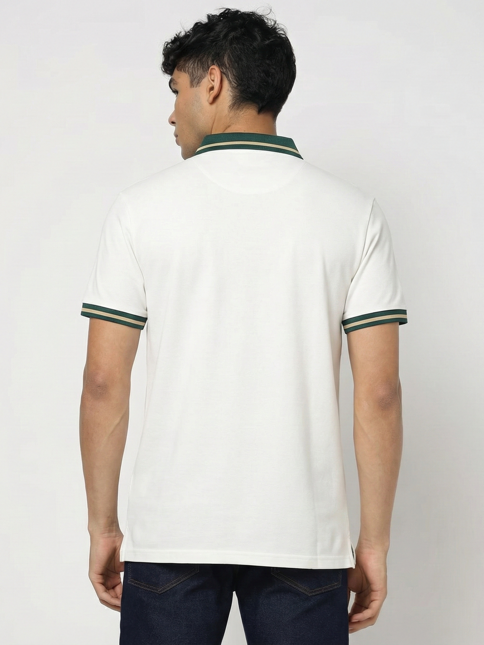 Person wearing a white polo shirt with green accents on a plain background